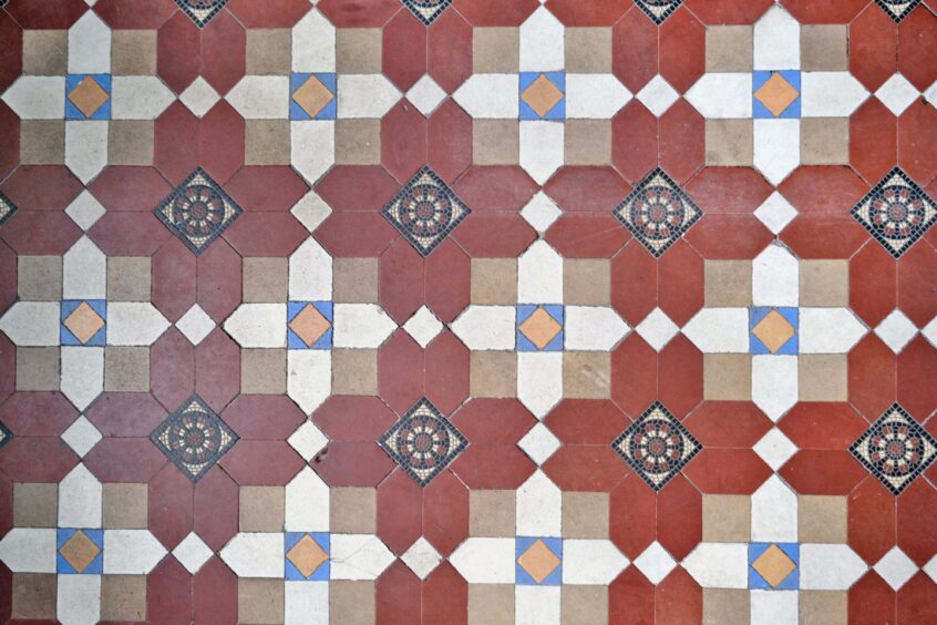 The mosaic floor tiles with shades of burnt orange, blue and beige