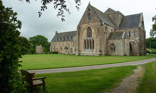 Exterior of Pluscarden Abbey looking across grounds.
