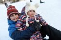 Boxing Day 2023 sledging on snow in Aviemore in the Cairngormsare Mitchell, 10, and Maisie, nine months.