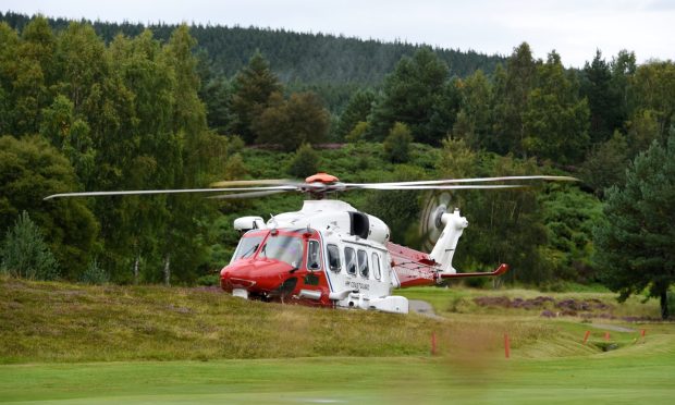 HM Coastguard helicopter landing in a green field.