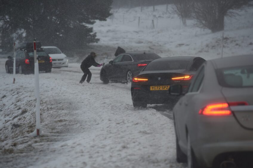 Person pushing their car in the snow on the A9.
