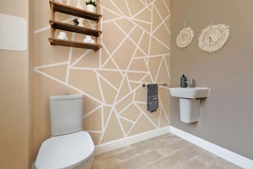 The bathroom with beige walls, macramé framed mirrors on the wall and hanging wooden shelves