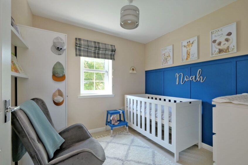 The nursery which has an armchair, crib, chest of drawers and framed prints of animals on the wall