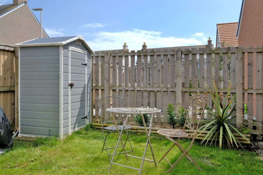 The back garden has a small shed and a set of metal garden furniture