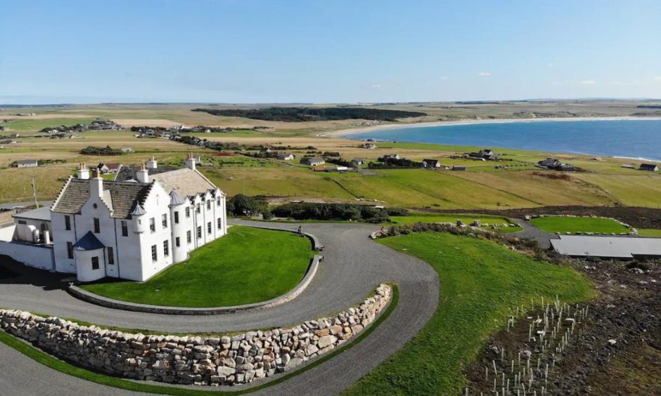 Aerial shot of The House of the Northern Gate with view of Dunnet Bay in the distance.