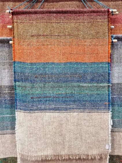 An abstract wall hanging made of striped of differently-coloured woven fabric.