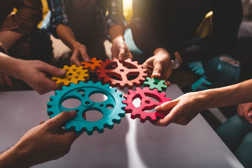 Teamwork of business people work together and combine pieces of gears.