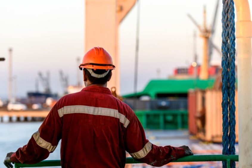 An offshore worker looks out to see with his back to camera.