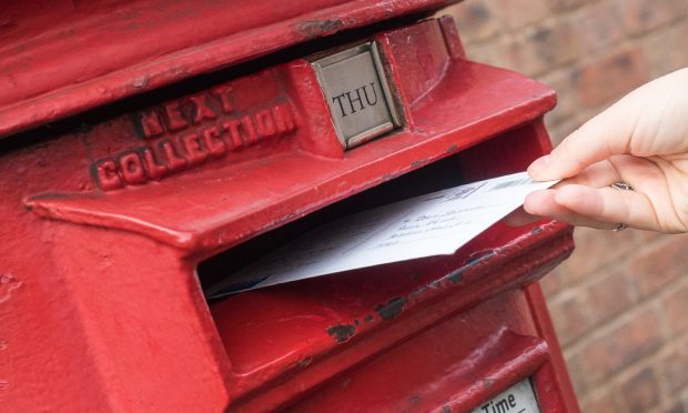 Hand putting letter into postbox.