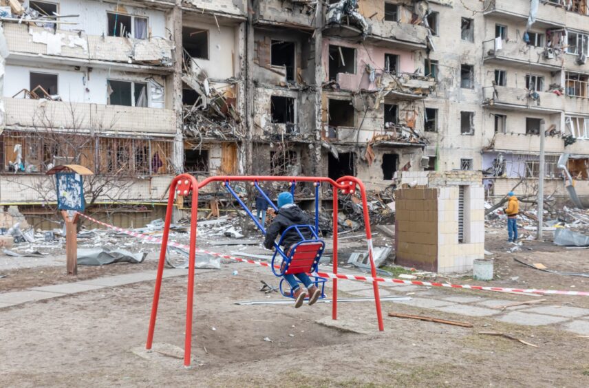 Child on swing in wwar-torn. Ukraine.