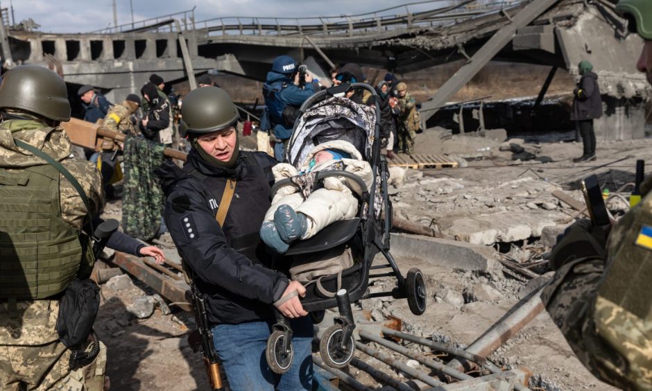 A baby is carried to safety from the rubble in Irpin in Ukraine. Image: Shutterstock.