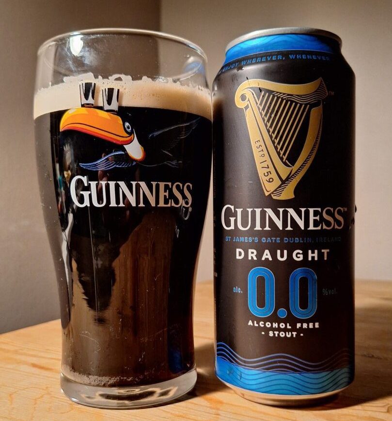 A can of Guinness 0.0 alcohol free beer, poured into a glass with a classic Guinness toucan on it. 