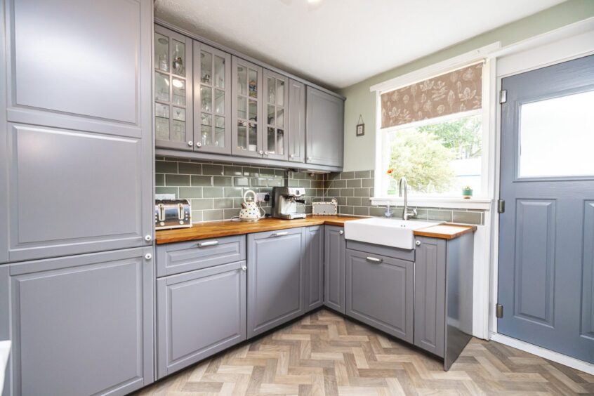 Stylish kitchen in the Aberdeen property, featuring grey cabinets and light herringbone flooring.