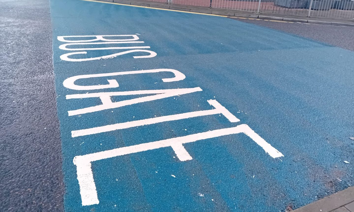 Blue road markings with white text reading 'Bus Gate'