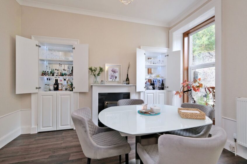 The dining room in the Aberdeen traditional property has a table with four plush grey dining chairs, fireplace and two shelved alcoves