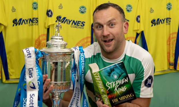 Buckie Thistle's John McLeod with the Scottish Cup trophy and Stephen King's novel The Shining.