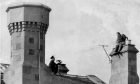 A prison officer seen trying to persuade an inmate at Craiginches to come down from a chimney during a rooftop drama which was captured on film by an Evening Express photographer in 1967. Image: DC Thomson