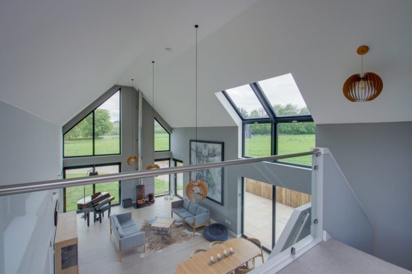 Glass panel on galleried landing overlooks the sitting and dining room in Drumview House 