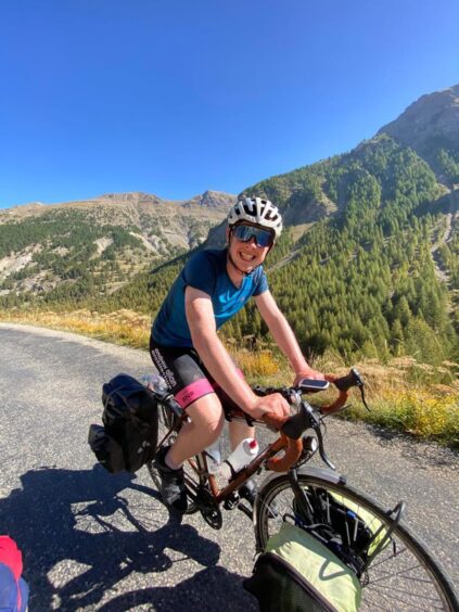 Robin on his bike against a blue sky and mountainous terrain.