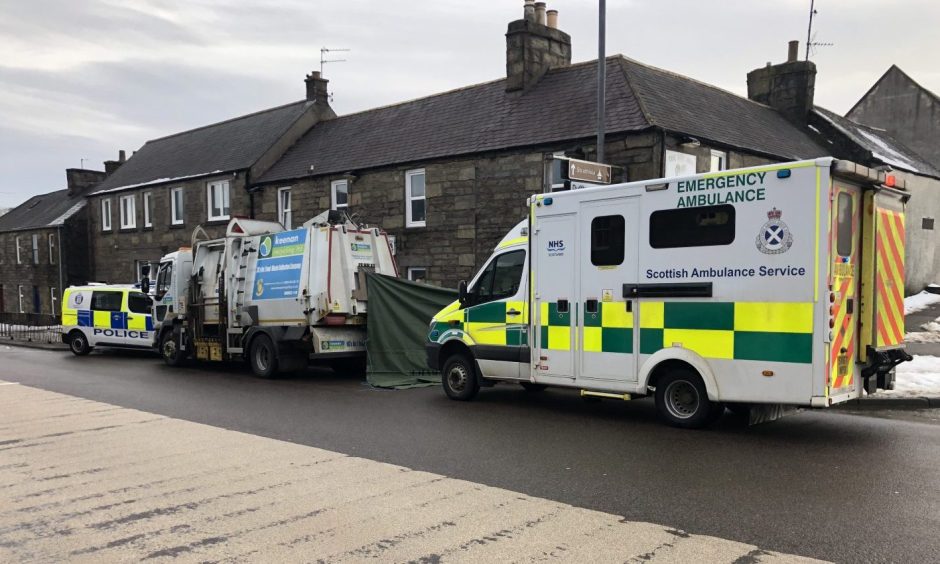 A police car, ambulance and recycling vehicle is parked outside a row of houses in Keith.