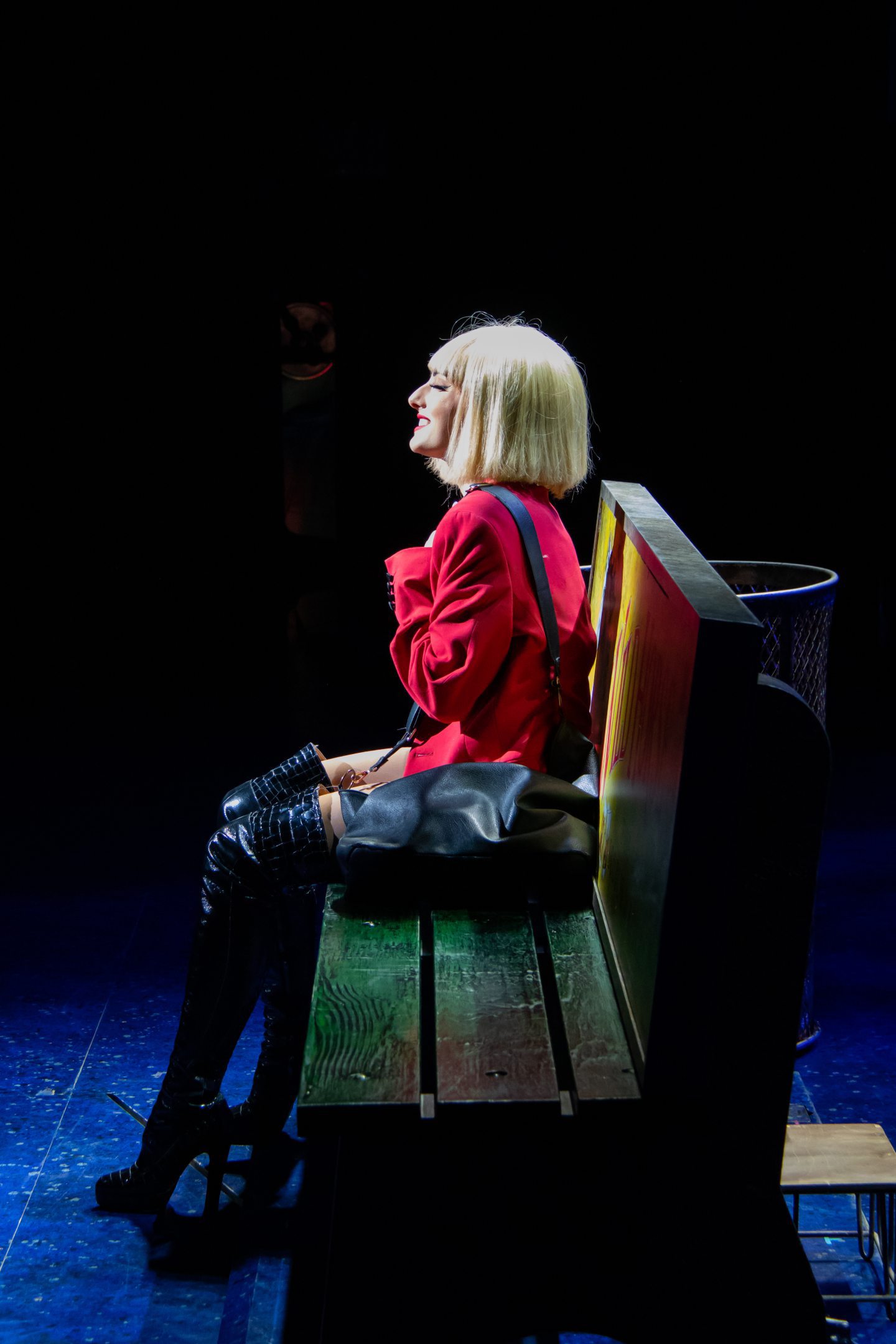 Elly Jay as Vivian Ward in the famous black knee-high boots and blond bob sitting on a bench in Pretty Woman the Musical coming to Aberdeen.