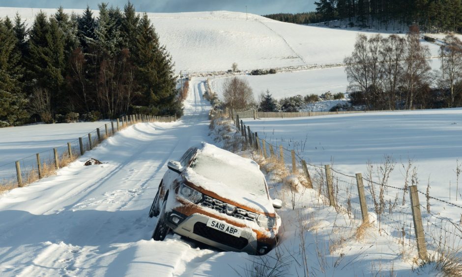 A car covered in snow on the side of the road.