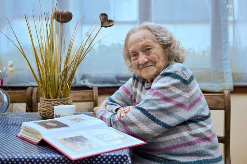 Inverness Holocaust survivor Kathy Hagler at home looking at a photo album.