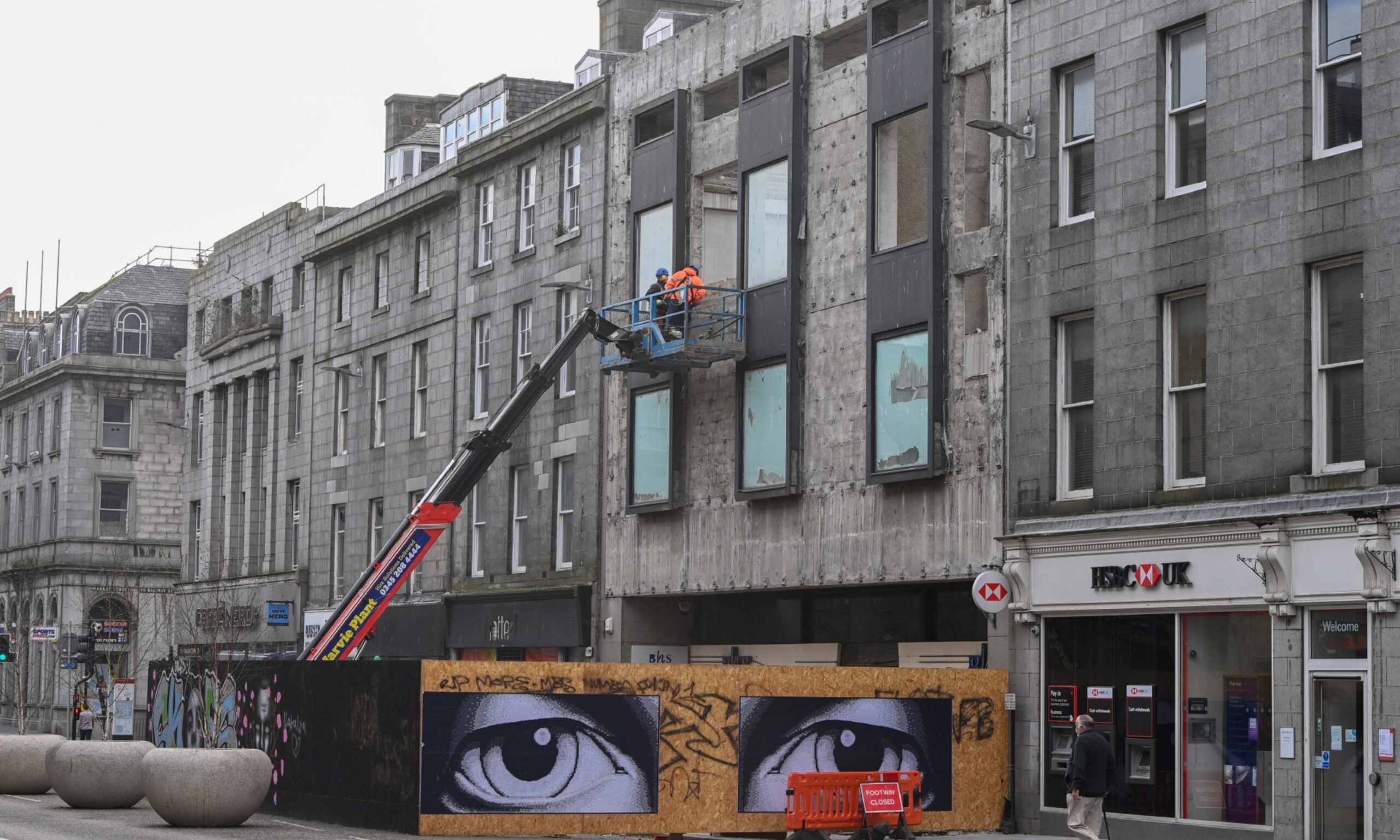 Two workers on a cherry picker taking parts of the Union Street building down