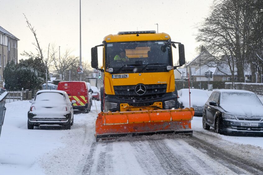 A snow plough helps clear roads amidst travel chaos.