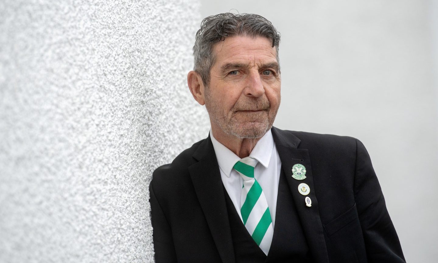 Garry Farquhar leaning against a white wall in club suit. 
