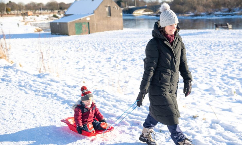 Fiona Shaw with Finn on a sled along the river Dee