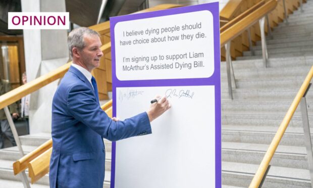 Lib Dem MSP Liam McArthur signs a pledge card in support of his Assisted Dying Bill at the Scottish parliament in 2022. Image: Jane Barlow/PA Wire