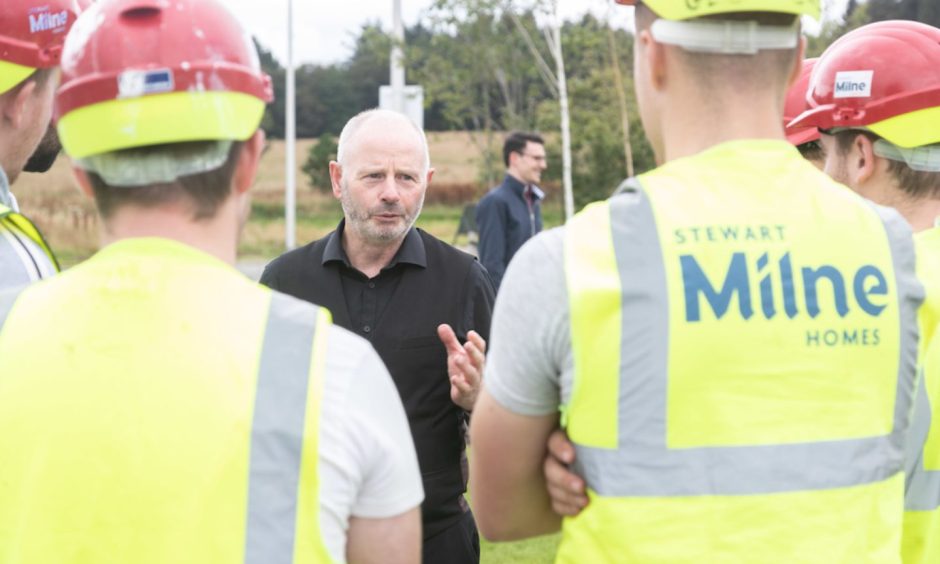 Construction entrepreneur Stewart Milne speaking with construction workers.