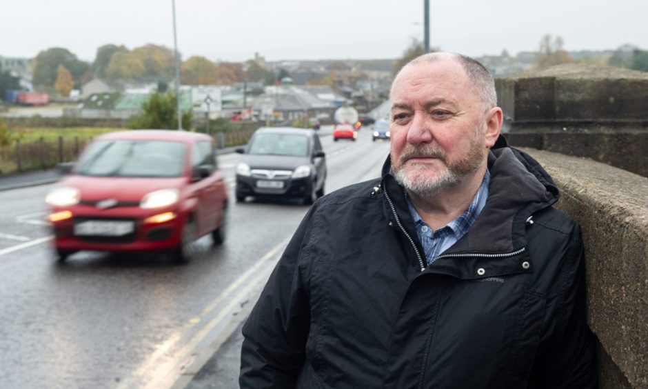 John Divers next to busy road in Elgin.