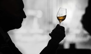 Silhouetted person holding up whisky glass.