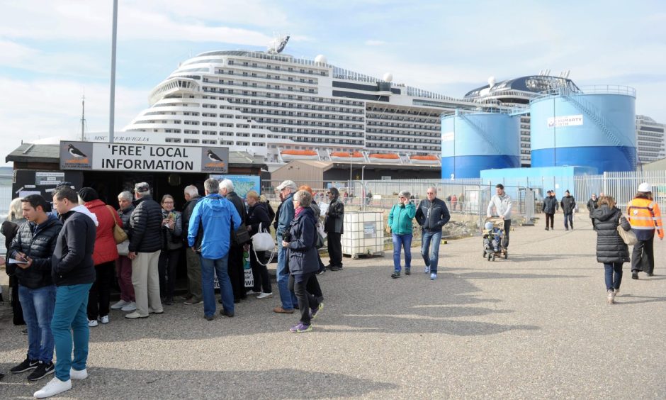 Cruise ship passengers on quayside with cruise ship behind.
