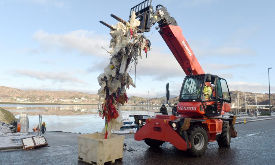 A digger holds up the debris collected from Strathan Bay.