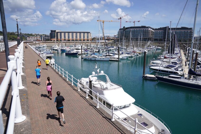 Joggers at a marina in Saint Helier, Jersey.