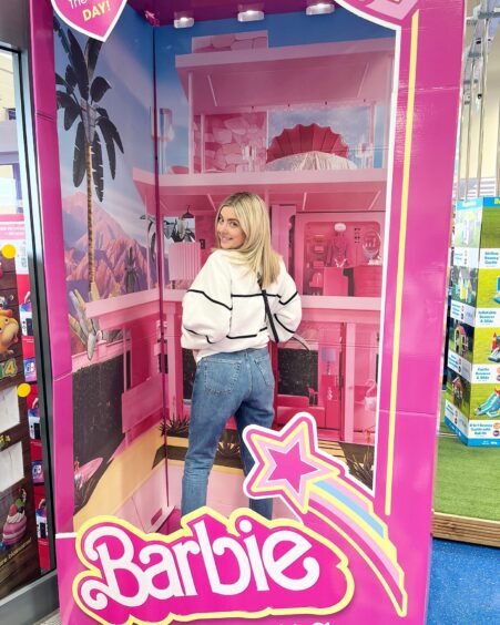 Samantha shows off her but while standing in a Barbie doll box in a toy shop