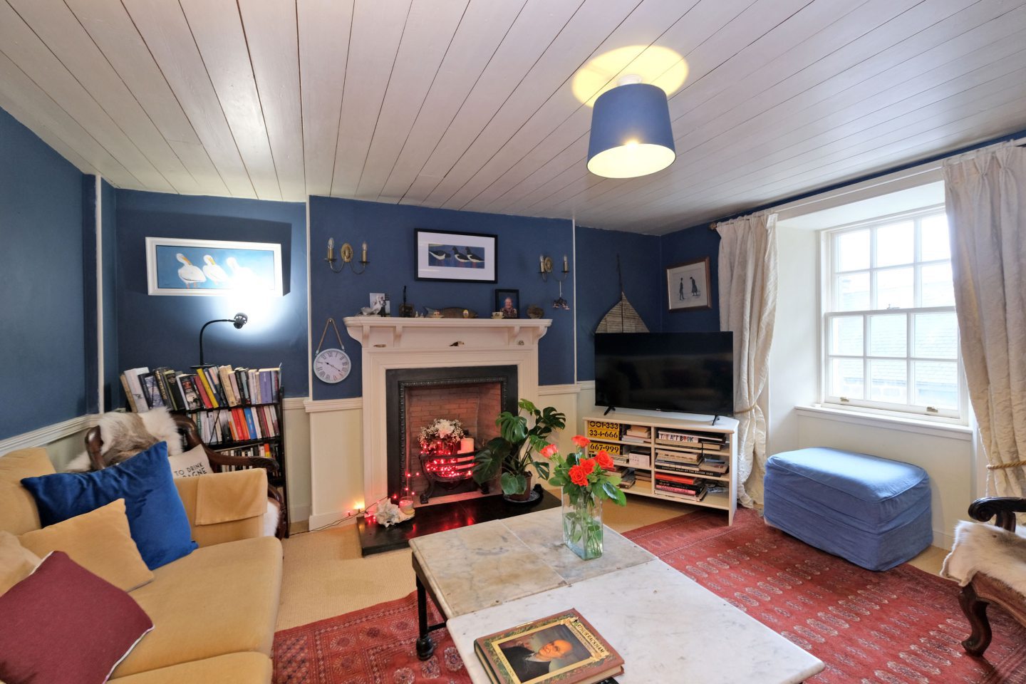 Cosy sitting area inside the Aberdeen artist's home featuring blue walls and white wood panelled ceiling.