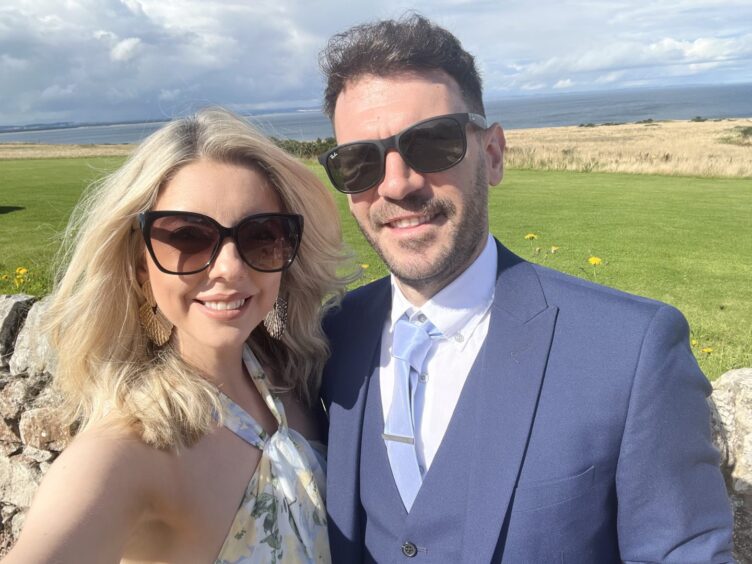 Samantha Leckie and her fiance Allan Ogston pose in front of a field and sea