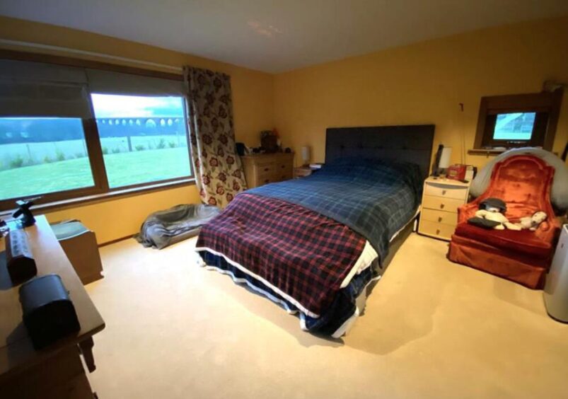 A large double bed, covered in a dark blue duvet,dominates one of four bedrooms in the property.