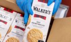 Hands lifting boxes of Walker's Shortbread Ltd
