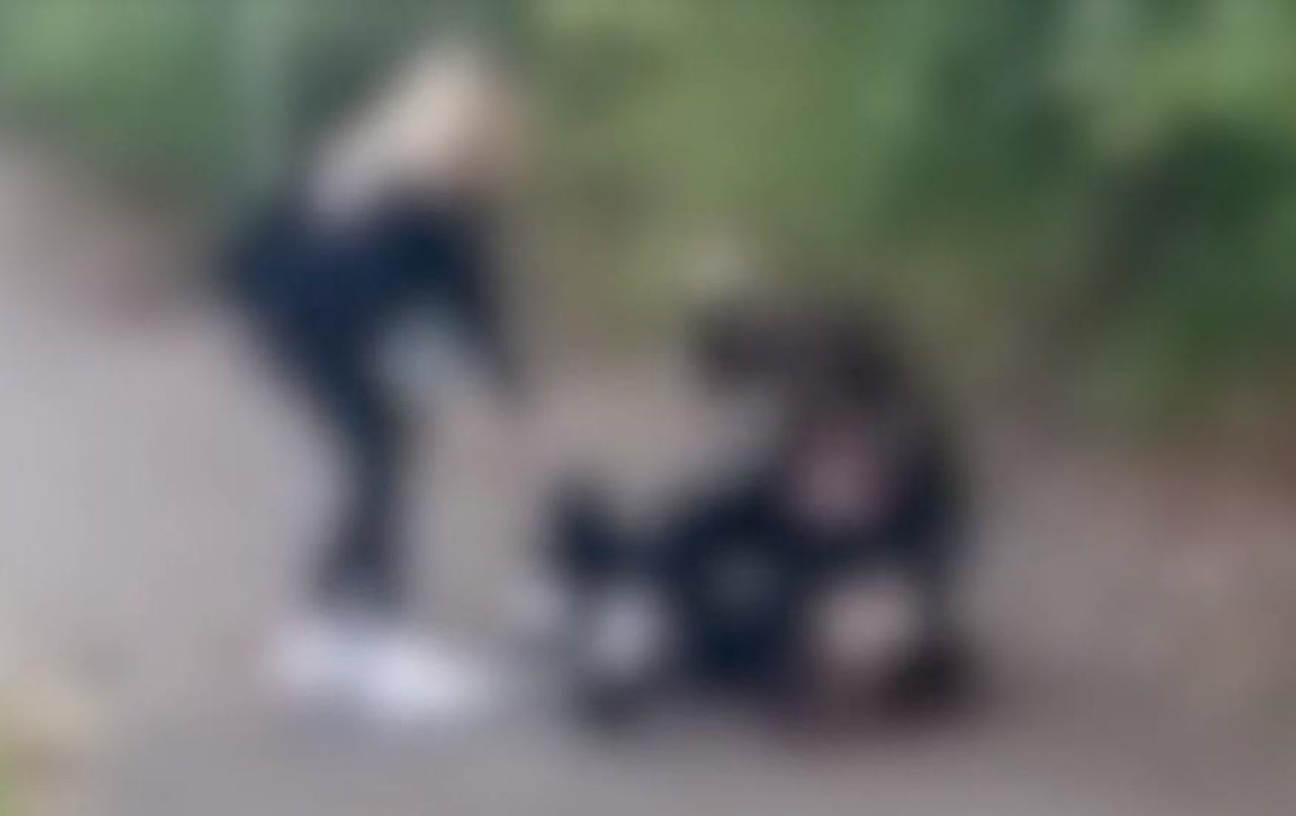 A blurred screenshot from a video of a pupil being attacked on the ground outside