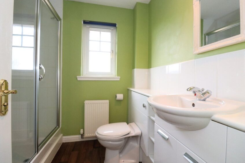 A bathroom with green walls and a cubicle shower
