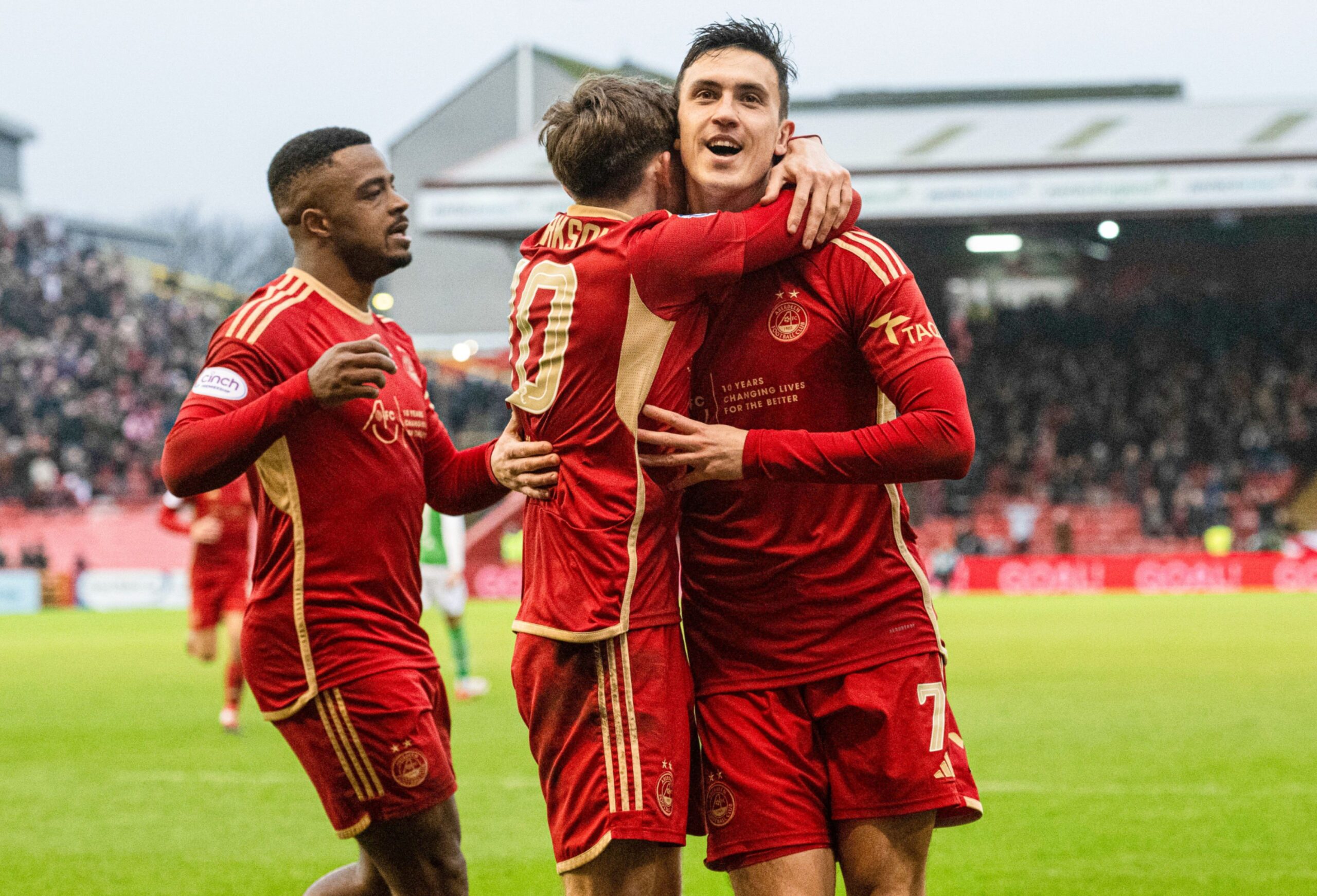 Aberdeen's Jamie McGrath celebrating with Leighton Clarkson and Duk on the pitch