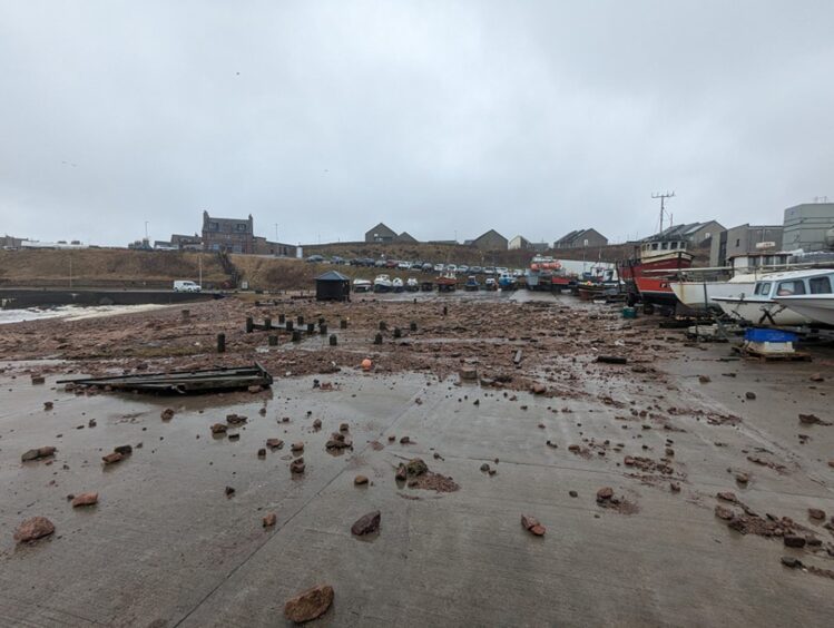 Boulders have been washed up onto the concrete of Boddam Harbour. 