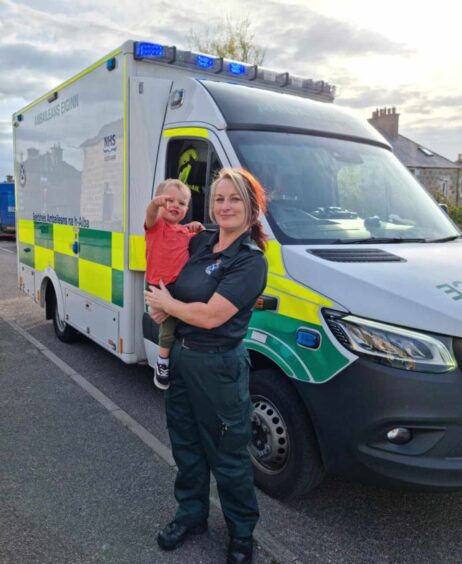 Elaine and her grandchild next to an ambulance. 