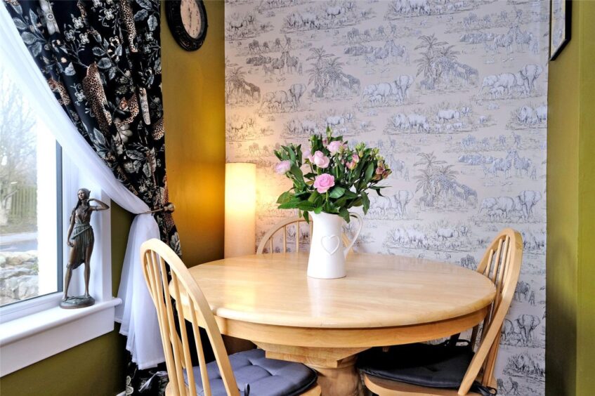 Cosy travel-inspired dining area with safari wallpaper.