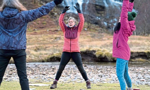 Wild Yoga instructor Penny Clay (centre) leads a session in the shadow of Steall Falls. Image: Sandy McCook/DC Thomson.